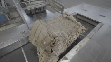 Forklift taşıma bandına bir balya atık kağıt yerleştirir. Mekanizma, daha ileri işlemler için karton fabrika atölyesine hammadde gönderiyor