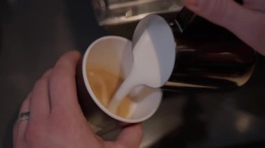 Sütlü süt akıntısı, köpükle şekillenen kahve kalbine döküldü. Sahne sıcaklığı ve yaratıcılığı yayar. Taze aromatik biraya mükemmel bir son.