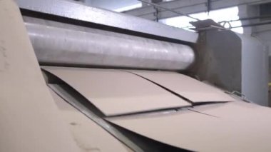 İş sırasında büyük bir karton seviyelendirme makinesi. Salon düz ve pürüzsüz karton çarşaflar oluşturmak için özel ekipmanlar içerir