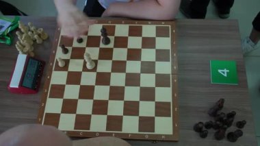Satranç tahtası oyunun son aşamasını gösteriyor ve içinde birkaç parça kaldı. Oyuncu eli, son hamlelerin gerginliğini vurgulayarak hareket etmek için yakalandı.