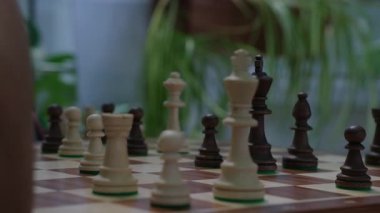 Erkekler masada oturan satranç oyununa derinden konsantre olurlar. Satranç tahtası Rooks Fil Şovalyeleri ve Piyonlar da dahil olmak üzere oyun taşlarıyla dolu.