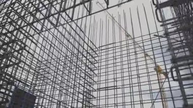 Büyük çelik takviye yapısı gelecekteki binanın iskeletini oluşturur. Metal çubuklar kesişiyor. Beton elementler için güçlü bir temel oluşturuyor.