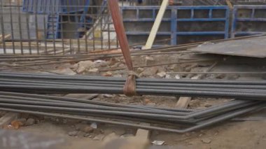İnşaat alanında vinç kaldırma demiri yığını. Metal çubuklar bağlandı. Taşıma ve takviye için kayışlar hazır.