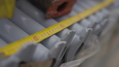 Metal yüzey boyunca kıvrımlı dokularla gerilmiş şerit. Gelecekteki inşaatlarda kullanılmadan önce incelenen materyaller