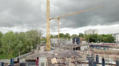 İnşaat halindeyken vinç malzemeleri taşır. Güçlendirilmiş beton ve çelik iskeletleri üzerinde çalışan inşaatçılarla dolup taşan site