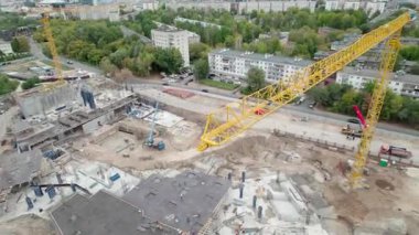 Uzun vinç büyük ölçekli inşaat sahasında çalışıyor. Kazılmış toprak ve ağır makine kontrast keskin kentsel görünüm ile