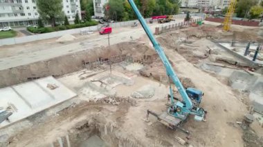 Yüzey metro istasyonu için aktif inşaat alanında büyük mavi vinç kaldırma malzemeleri bulunuyor. Araçları ve konut binaları olan yakın karayolu kentsel düzeyi vurguluyor