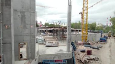İnşaatçılar çelik destek çubukları ve inşaat alanından çıkan beton sütunlarla temel etrafında yürürler. Devam eden yapısal çalışmaları olan metro istasyonu inşaatı
