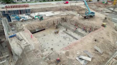 İşçiler derin kazı sahasının etrafında dayanıklı beton yapısı oluşturuyorlar. Malzeme işleme ile birlikte kazmak için kullanılan ağır makineler