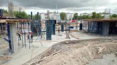 Çalışanların farklı sorumluluklar taşıdığı tren istasyonu inşaat alanı. İnşaat alanı sağlam beton oluşumlar ve kazılmış bölümler içeriyor