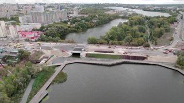 Geniş köprü, şehrin yoğun nüfuslu bölgesinden akan nehri geçer. Havadan bakıldığında yoğun yeşilliğin üzerinde yükselen sayısız yüksek binalar görülüyor.