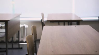 Düzenli masalar ve sandalyeler sessiz boş sınıfları kapatıyor. Odanın sessiz uğultusu bir sonraki canlı dersin beklentisini yansıtır