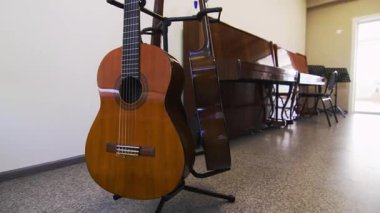 Akustik gitarlar birbirine yakın bir şekilde dinleniyor ve bu da karmaşık ahşap işçiliğini gösteriyor. Müzik sınıfının canlı atmosferi yaratıcılık ve öğrenme vaat ediyor