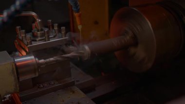 Torna teçhizatlı demir parçası üzerinde çalışan hortumla matkap patlamaları. Püskürtme mekanizması metali sürekli olarak soğutur