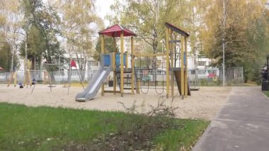 Slaytlar, ağaçların arasındaki tırmanma kareleri ve kaldırımlar da dahil olmak üzere renkli oyun yapıları olan kumlu oyun parkı. Çocuklar için yerleşim alanı