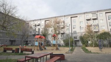 Apartmanın avlusundaki oyun parkında bulutlu gökyüzünün altında renkli oyun yapıları var. Çocuklar için alan sağlayan sakinler için dinlenme alanı