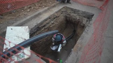 Ağ ile çevrili kanalizasyon çukuruna drenaj ekipmanı kurulmuş. Seslendirilmiş işçi tedavi verimliliği için sistemi dikkatlice kurar