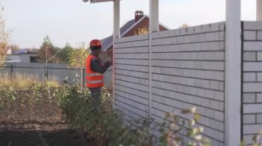 ALMATY, KAZAKHSTAN - 19 Mart 2025: İnşaatçı inşaat alanında görünümünü artırmak için tuğla çit boyuyor. Boyama süreci çitleri hava koşullarından iyi korur.