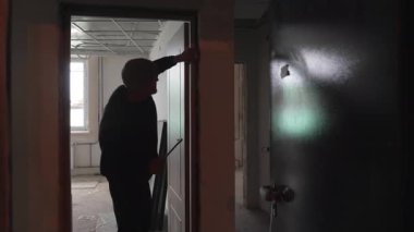 ALMATY, KAZAKHSTAN - 19 Mart 2025: yetenekli marangoz bina iskelesine kapı monte eder. Kurulum, oda işlevselliği ve güvenliği için giriş yapısını tamamlar