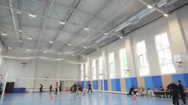 ALMATY, KAZAKHSTAN - 19 Mart 2025: öğrenciler modern kapalı spor salonunda voleybol oynuyorlar. Parlak ışıklandırma ve ferah mahkeme takım çalışmasını koordinasyonla birlikte geliştirdi