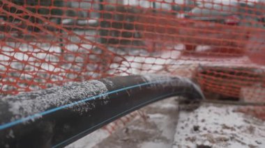 Uzun drenaj hortumları karla kaplı zemini kaplıyor çitli lağım çukurunda kayboluyor. Sistem aktif olarak atık suyu kaldırmak için çalışır