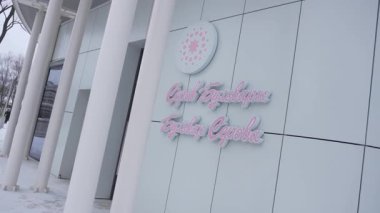 Karla kaplı parkta fayanslı bina sessizce duruyor. Dikdörtgen tasarım ve görünür park adı, kimlik ile birlikte kamusal alanların önemini vurgular
