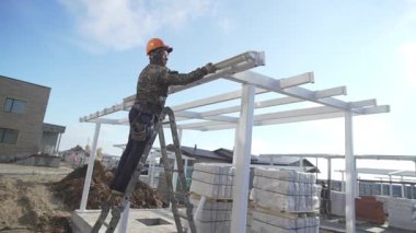 ALMATY, KAZAKHSTAN - 19 Mart 2025: İnşaatçı demir kirişleri kullanarak veranda yapısını monte ederek drenaj borusunu tasarıma entegre eder. İnşaat binaların işlevselliğini artırır