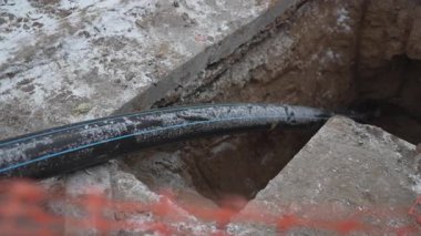 Kalın kauçuk hortum bakım çalışmaları devam ederken kanalizasyon çukuruna doğru uzanıyor. Kamu çalışanları sistemin işlevsel kalmasını sağlar. Tıkanıklıkları ve taşkınlıkları önlüyor