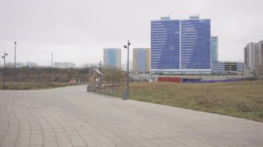 Konforlu banklarla kaplı Paved geçidi renkli modern gökdelenlere açılıyor. Gelişmiş şehirde manzara ve rahatlama yolu