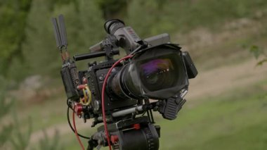 Profesyonel sinema kamerası yaz günü çimenli çayıra kurulmuş. Yüksek kaliteli videolar kaydetmek için sağlam üç ayaklı özel ekipman