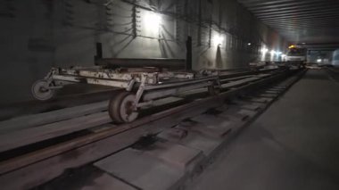 İnşaat arabası metro bölgesinin derinliklerinde metro rayları boyunca sorunsuz ilerliyor. Karanlık tünelde tekerlekler sessizce patlar. Malzemeleri teslim etmek için kullanılan araba.