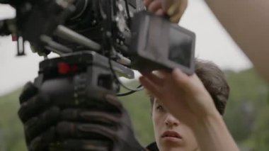 ALMATY, KAZAKHSTAN - AĞUSTOS 05 2024: Genç asistan sabit çekim için kamerayı tripoda destekler. Harekete geçmeden önce mükemmel çerçeve gerekli. Denge düzgün hareket için kontrol edildi