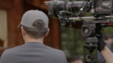 ALMATY, KAZAKHSTAN - AĞUSTOS 05 2024: Baştaki ekip üyesi kameralı tripodun yanında duran telsizle yön tarif ediyor. Koordinasyon her bölümün hazır olmasını sağlar