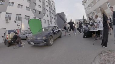 ALMATY, KAZAKHSTAN - Ağustos 05 2024: Kadın sürücü motoru çalıştırmaya çalışırken aktör aracı itiyor. Sahne, hikayeye gerçekçilik katar. Yönetmen otantik tepkilere odaklanıyor