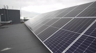 Büyük güneş paneli bulutlu gökyüzünün altında çatıya doğru uzanıyor. Temiz enerji sistemi sürdürülebilirlik ve yeni teknolojilere odaklanmayı yansıtır