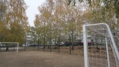 Kapalı futbol sahası yüksek ağaçlar ve konut binaları arasında yer alır. Huzurlu mahalle spor alanı banliyö yaşam tarzını yansıtıyor