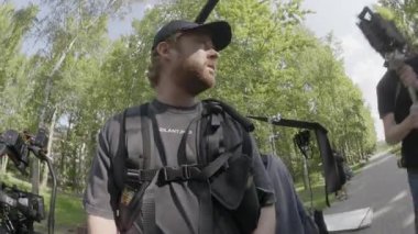 ALMATY, KAZAKHSTAN - AĞUSTOS 07 2024: film çekimi. Yönetmen rehberlik ederken film ekibi parkta çekim yapmaya hazırlanıyor. Çalışanlar çalışırken kamera teçhizatı özenle halledildi