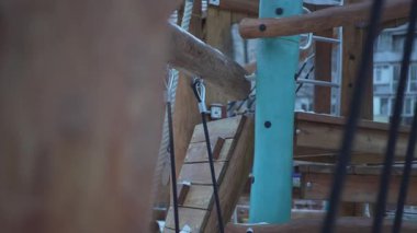 Çelik kaydırak ve ağları karlı arazide duran ahşap oyun alanı yapısı. Apartman binaları donuk sahnenin arkasında yükseliyor ve derinlik katıyor