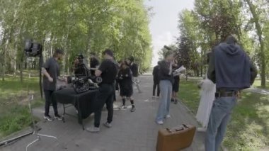 ALMATY, KAZAKHSTAN - AĞUSTOS 07 2024: film çekimi. Film ekibi kamera donanımı kurun ve ekipmanları kontrol edin. Teknisyenler ekipmanları ayarlar ve güneşli park alanındaki hazırlıkları tamamlarlar.