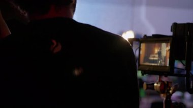 ALMATY, KAZAKHSTAN - AĞUSTOS 07 2024: film çekimi. Direktör kameraya dikkatlice bakar. Ekip üyeleri ara sıra devam eden film çekimlerinde yanımızdan geçerler.