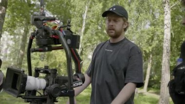 ALMATY, KAZAKHSTAN - AĞUSTOS 07 2024: film çekimi. Adam kamera düzeneğini küçük ekranı göstererek açıklıyor. Başka bir adam açık hava çekimi sırasında video ayarlarını gözlemler ve tartışır