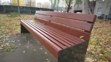 Düşen sonbahar yaprakları renkli oyun parkının yanındaki bankta nazikçe dinlenir. Huzurlu sonbahar atmosferi konforlu yerleşim alanıyla doludur.