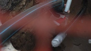 Uzun kauçuk hortumlu yılanlar kanalizasyon çukuruna. Elektrik işçisi drenaj ekipmanlarını bağlıyor. Güvenli ve düzgün kurulum sağlanıyor