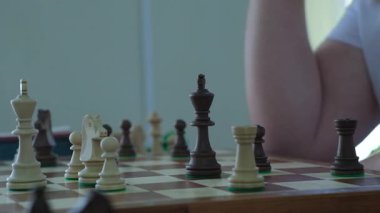 Satranç tahtası üzerinde uzun süre çalışan bir adam, şahı rahatça hareket ettirmeden önce. Oyuncu parçayı hareket ettirir ve panonun arkasındaki zamanlayıcıya basar