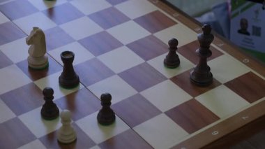 Satranç oyuncusu kendinden emin ve hızlı bir şekilde şahı öne çıkarıyor. Rakibi takip ediyor ve düşmana saldıran şövalyeyle agresif bir hamle yapıyor.