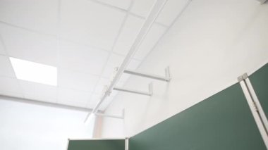 Modern sınıfta duvarın üzerine monte edilmiş modern tahta ve lamba var. Parlak öğrenim alanı gelecek öğrenciler için hazır.