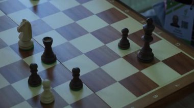 Tahta oyulmuş satranç taşları sessiz oyun sırasında tahta tahtada durur. Erkek eli şahı alır ve hızlı bir şekilde ilerler.