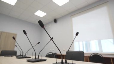 Konferans mikrofonları toplantı masasının üzerinde, parlak odada. Modern ekipmanlar iş ortamında profesyonel tartışmaları destekliyor