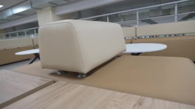 Açık deri koltuklar bekleme salonundaki yuvarlak masaların yanında duruyor. Oturma unsurları modern kamusal alanda son kurulumu bekliyor