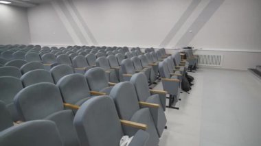 Oturma odasındaki sandalyeler sessiz salonu dolduruyor. Yumuşak ışıklandırma pastel duvarları parlatırken düzenli düzen modern eğitim atmosferini destekler.